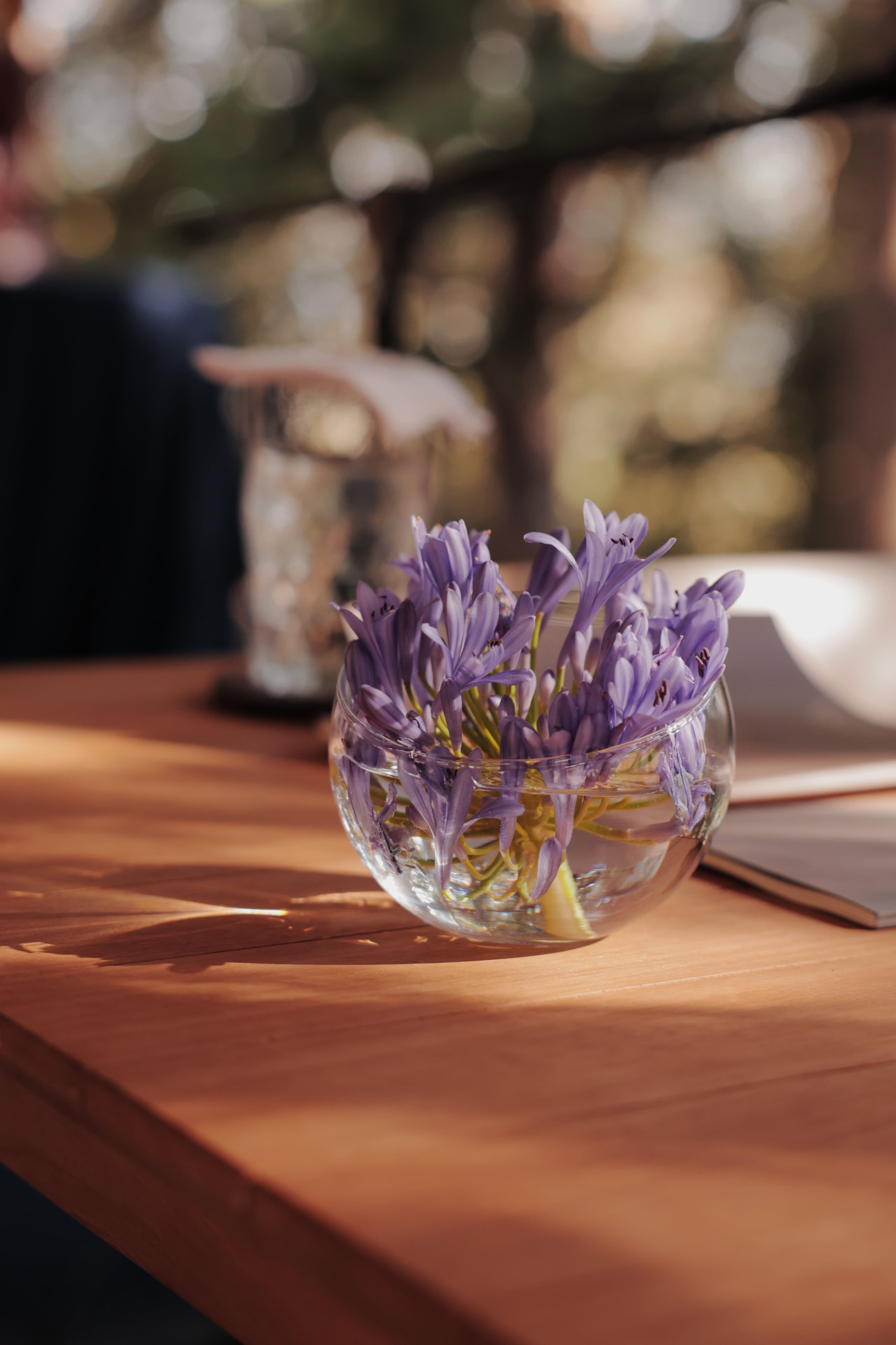 Spherical vase with lilac flowers on a wooden table 