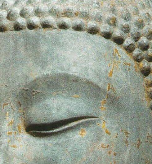 Detail of the face of a stone Buddha statue with remnants of gold