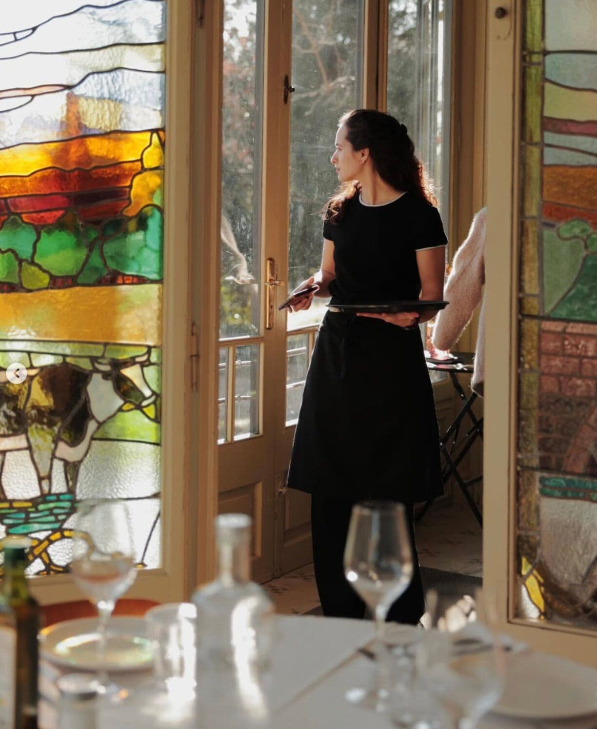 Amrita waitress beside the stained glass windows of the dining room
